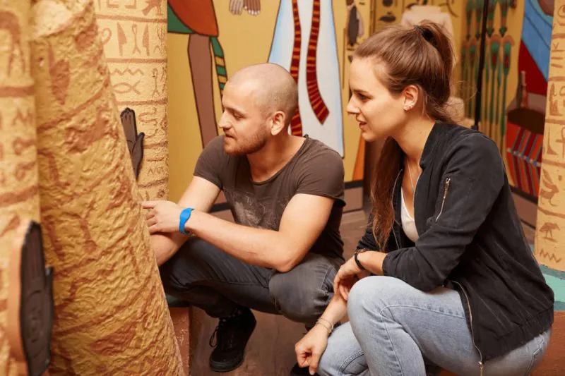 Team kniet vor einer Hieroglyphen-Wand und löst ein Rätsel