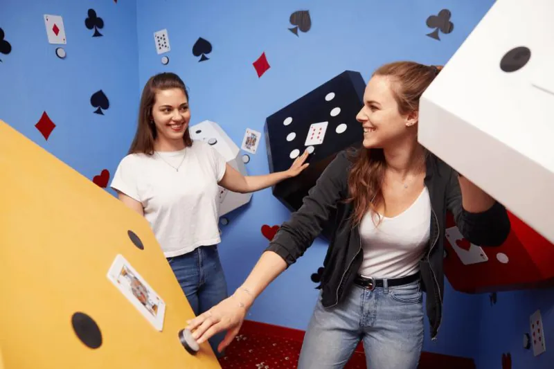Zwei Spielerinnen drehen einen riesigen Würfel im Casino-Raum