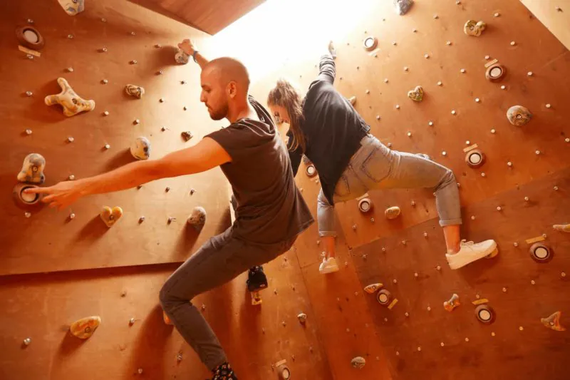 Zwei Spieler klettern an der Kletterwand eines Action-Raums